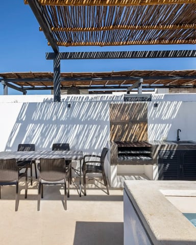 Terraza en la azotea con mesa de comedor, pérgola de bambú, parrilla integrada y piscina privada en MOMA PH, Aldea Zama